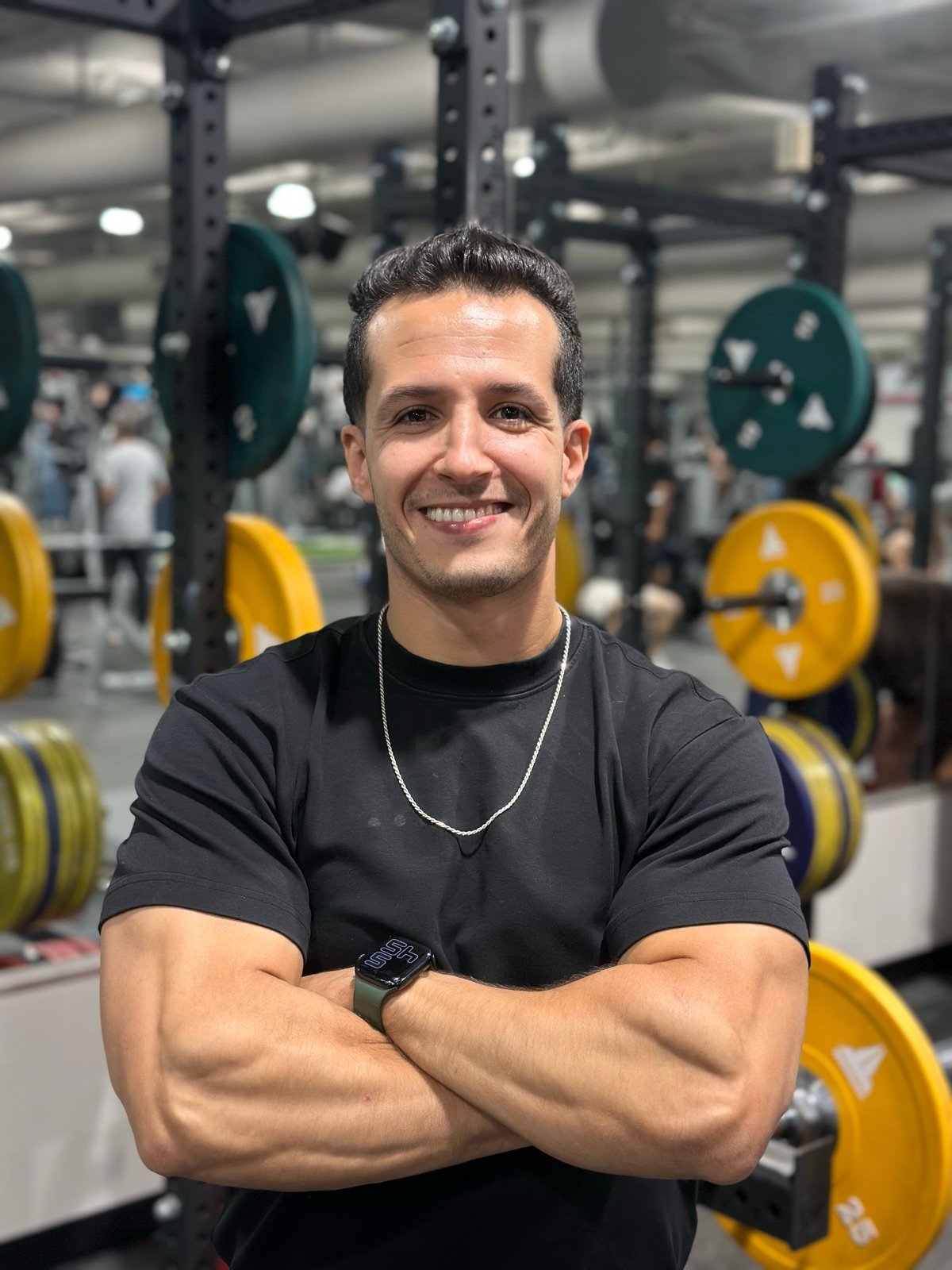 Neo, personal trainer, smiling with arms crossed in the gym